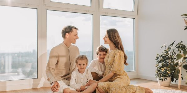 A joyful family sits together in a sunlit living room, fostering warmth and connection.